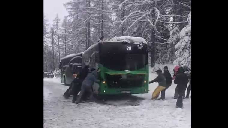 Drumul spre vacanță s-a transformat în test de forță: pasageri surprinși împingând autobuzul blocat în nămeți, pe ruta Poiana Brașov
